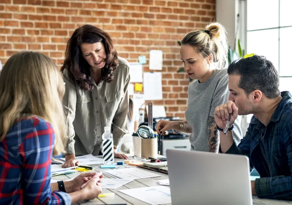Enseignante guidant une équipe de créatifs autour d'une table de travail