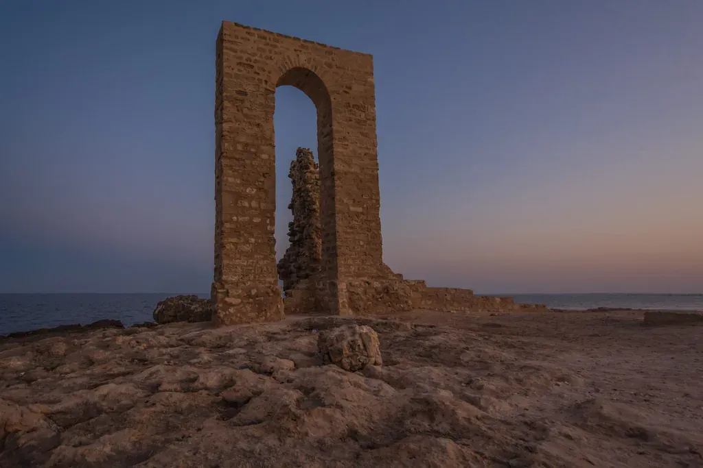 L'arche de pierre de Bab Bhar dressée sur la pointe rocheuse du front de mer de Mahdia, au crépuscule