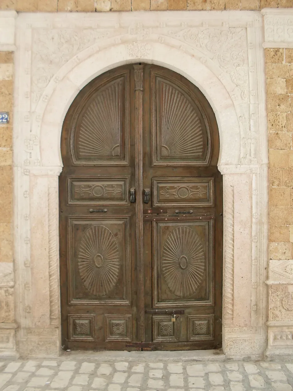 Porte traditionnelle sculptée sous arc en fer à cheval dans la médina de Tunis