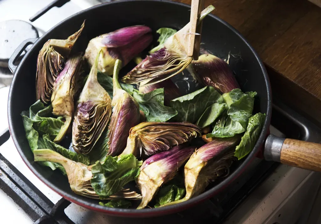 Cœurs d'artichauts poêlés aux feuilles vertes dans une sauteuse