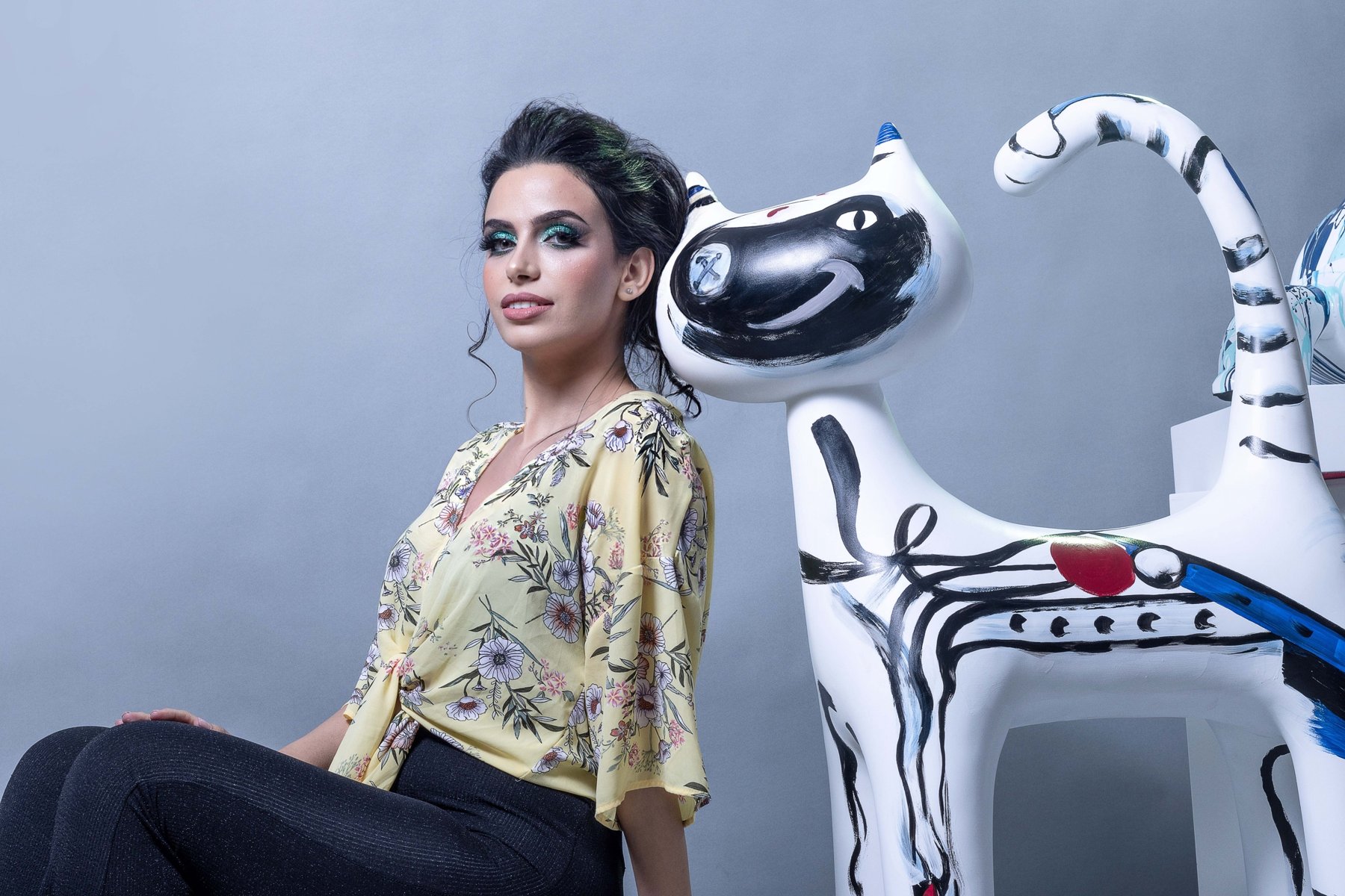 Femme en veste imprimée colorée, assise dans un décor graphique