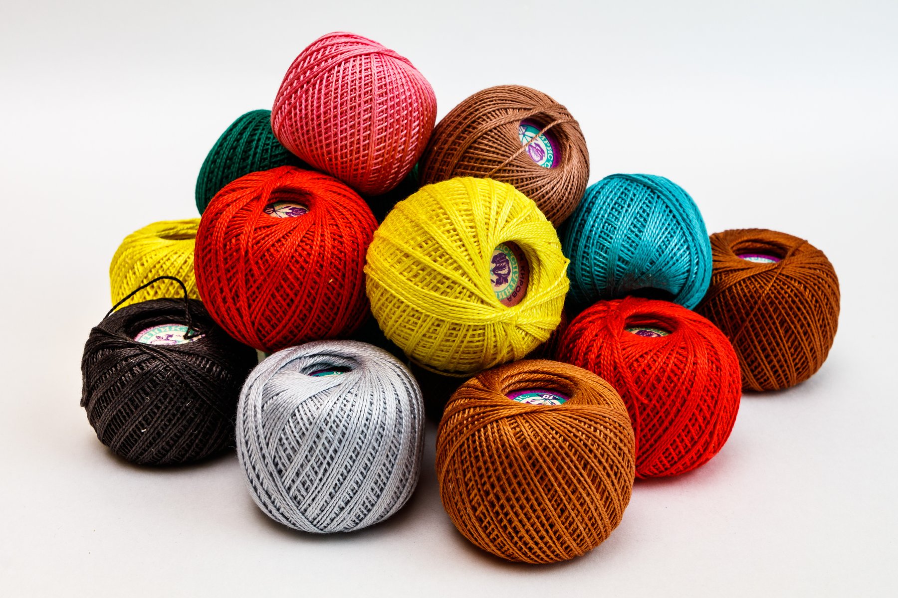 Pelotes de fil de crochet en coton de différentes couleurs empilées sur fond clair