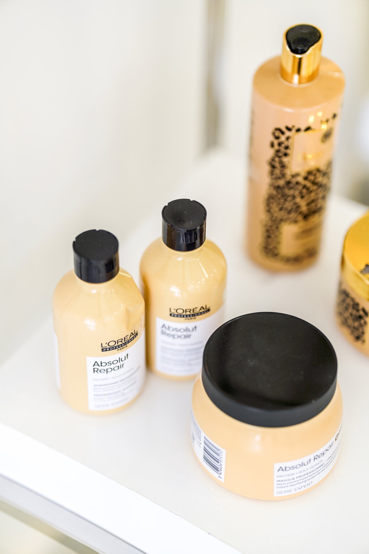 Flacons et pots de soins cosmétiques dorés disposés dans un institut de beauté