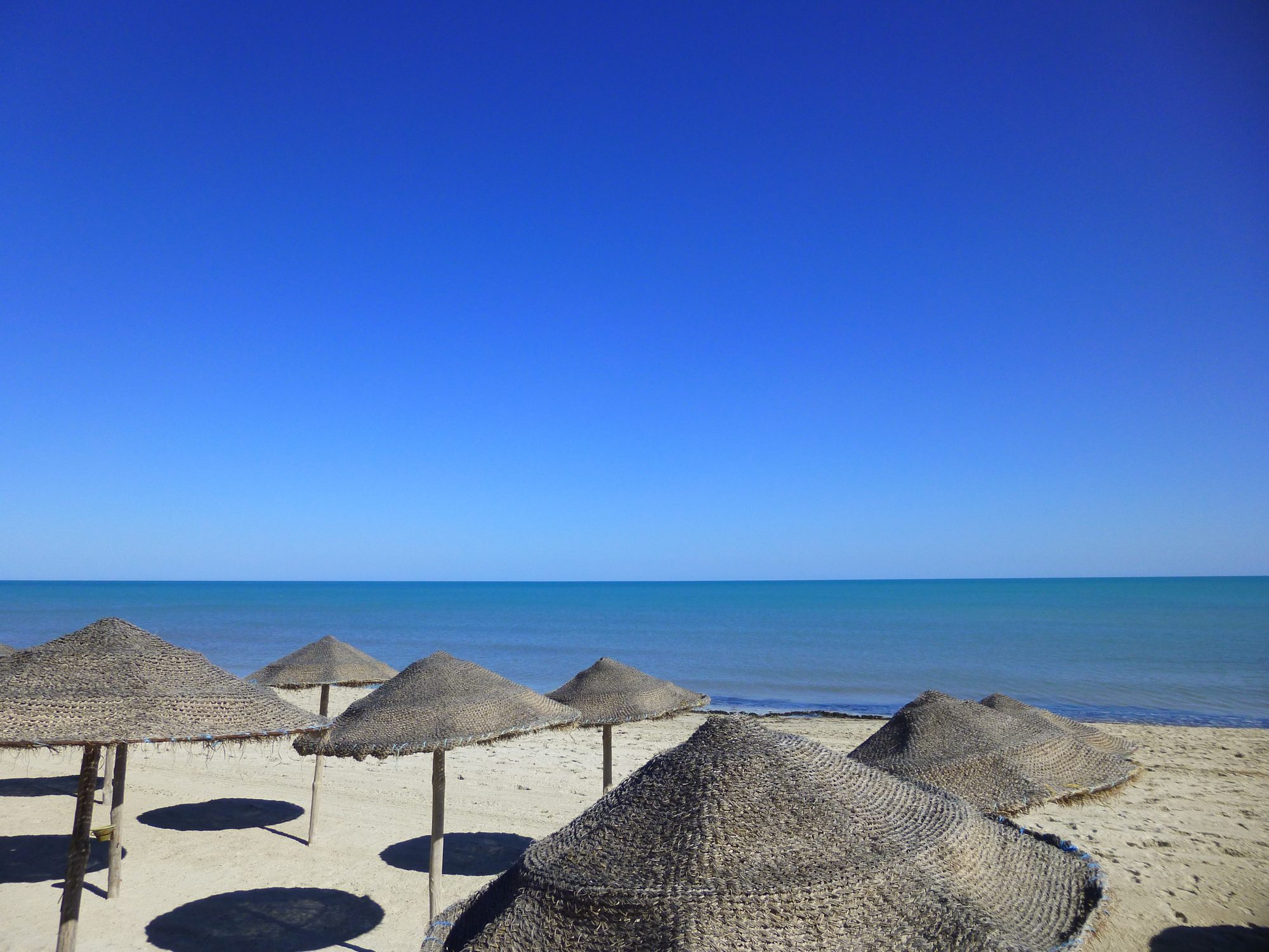 Plage djerba parasols — illustration de l'article « Djerbahood, l'incroyable aventure de Mehdi Ben Cheikh »