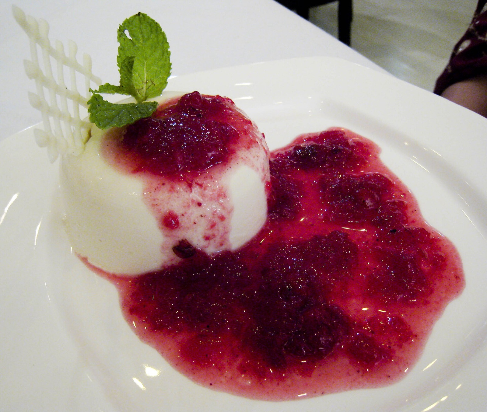 Dessert crémeux à la vanille nappé d'un coulis de fruits rouges et menthe fraîche